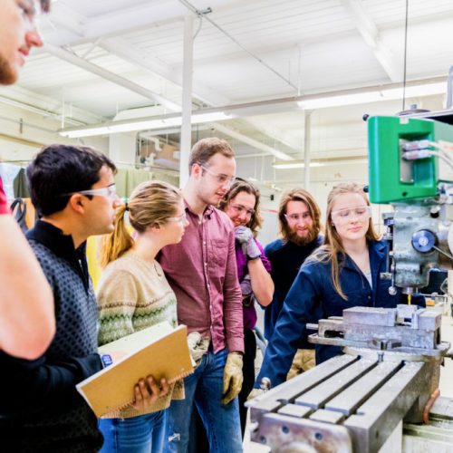 STEM, Education, University - Team of Engineering Students learning how to operate a heavy industrial machinery taught by a senior female student